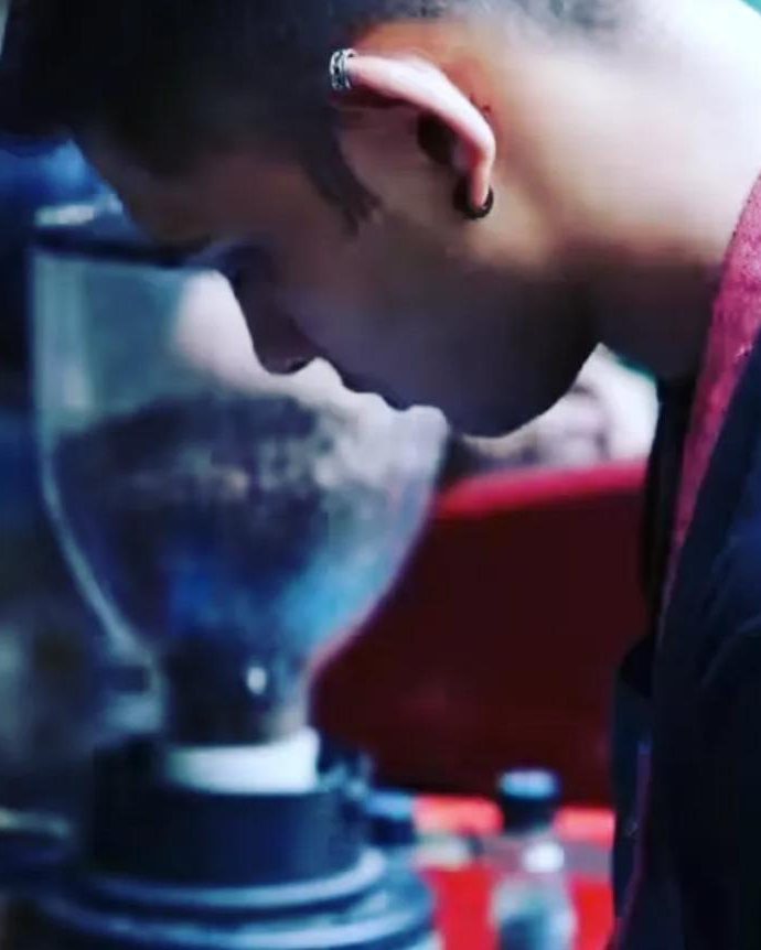 A barista watching the coffee grinder closely