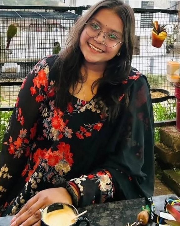 A smiling guest with a coffee, parakeets in the background