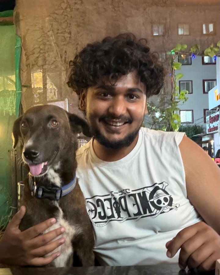 A guest smiling next to a dog at a cafe table