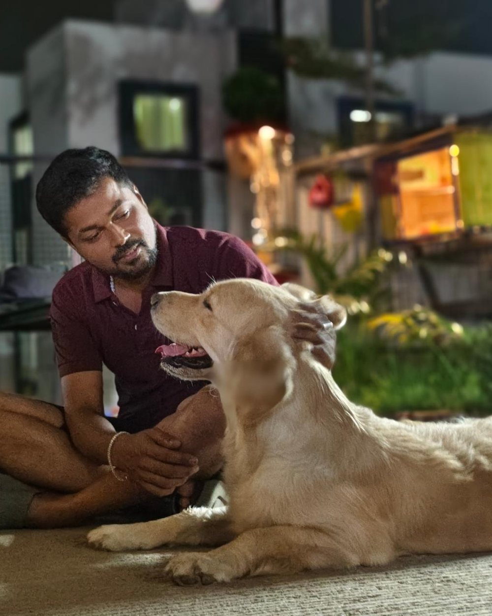 A guest sitting on the floor petting a golden retriever at the cafe