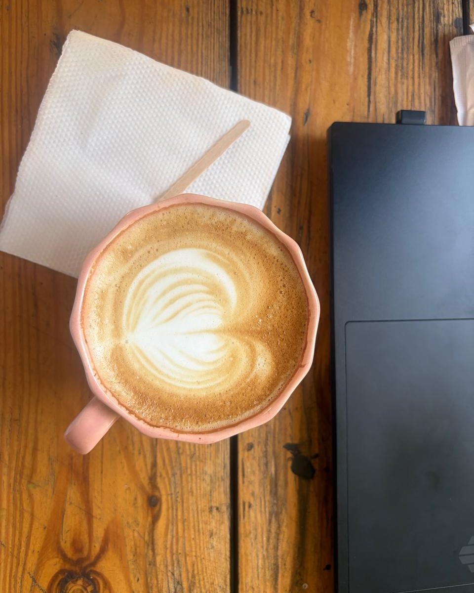 Latte art in a pink cup on a wooden table