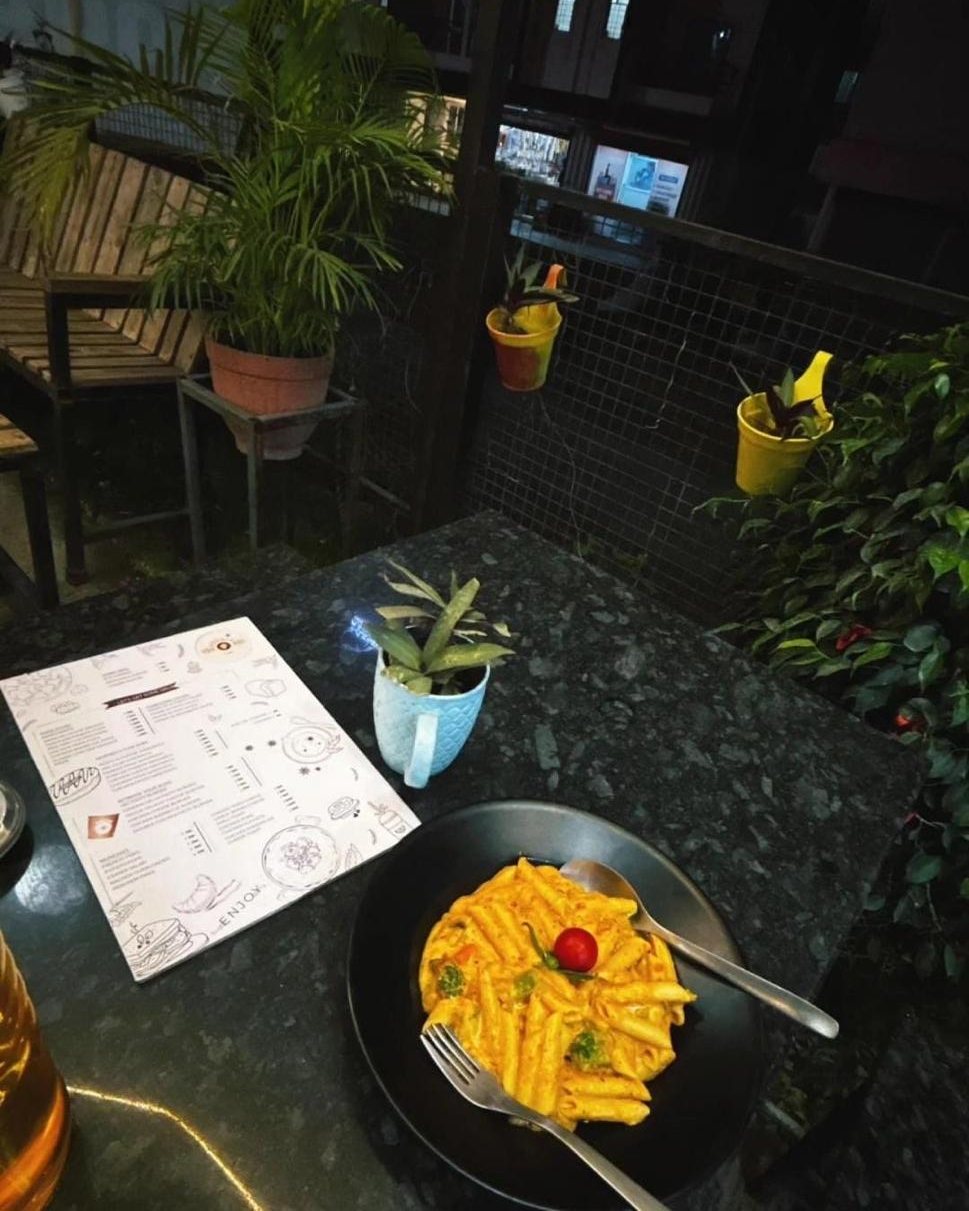 A plate of penne in a creamy orange sauce beside the menu, at night