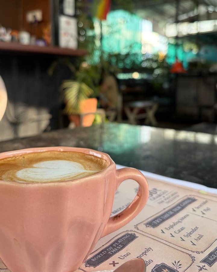 A cappuccino in a pink cup next to the board-games list