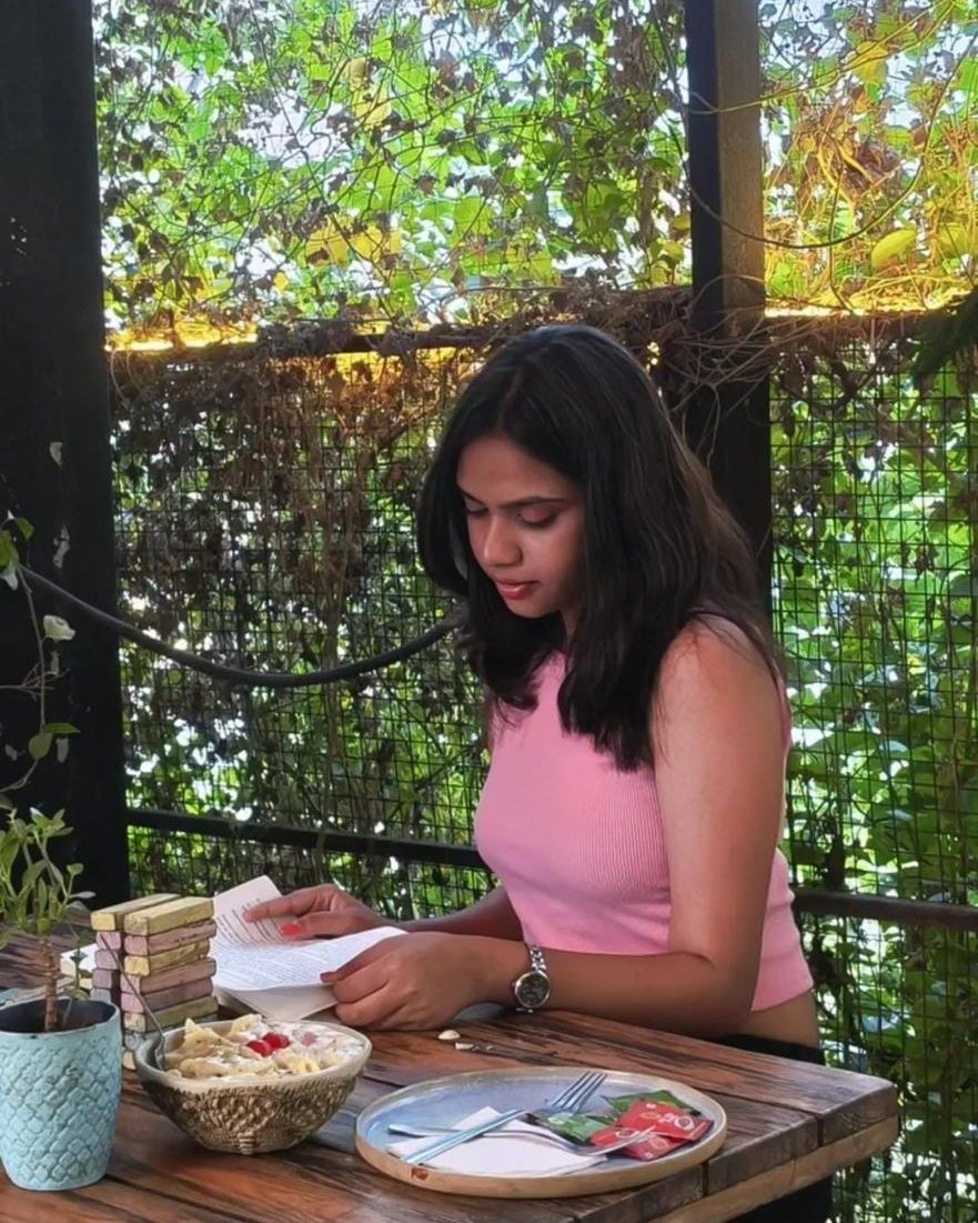 A guest reading at a wooden table surrounded by greenery
