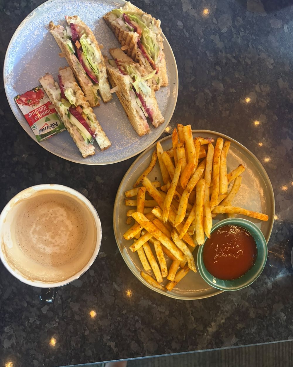 A club sandwich, masala fries with ketchup and a coffee, seen from above